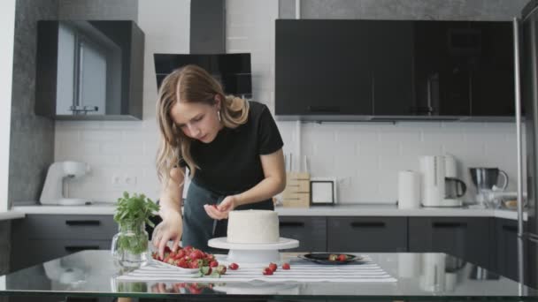 Professionell kock lagar tårta. Ung attraktiv hemmafru använder metall spatel justerar vit grädde på chokladkaka — Stockvideo