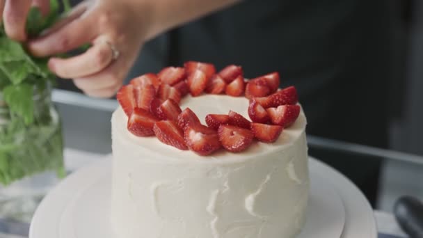 Chef profissional está cozinhando bolo. Close up de mulher coloca morango em cima de um belo bolo branco em uma cozinha moderna — Vídeo de Stock