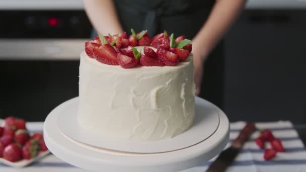 Profi-Koch kocht Kuchen. Nahaufnahme von schönen weißen Kuchen mit Erdbeere auf der Oberseite in einer modernen Küche — Stockvideo