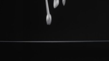 Beyaz çay kaşığı siyah arka plan yavaş çekim videosuna düşer.