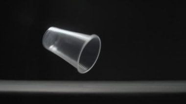 Plastik bardaklar siyah arkaplan yavaş çekim videosuna düşer.