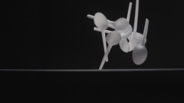 Білі ложки падають на чорний фон повільне відео руху . — стокове відео