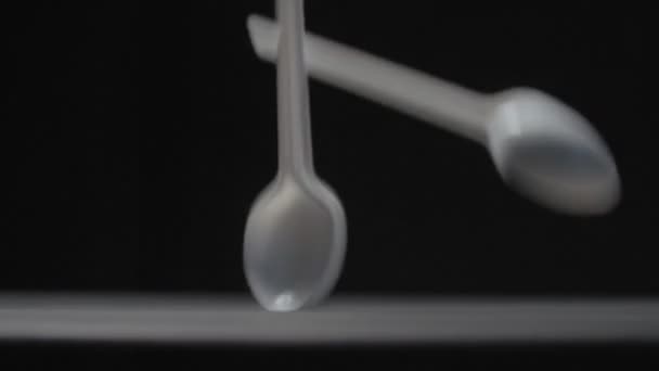 White spoons falls on black background slow motion video. — Stock Video