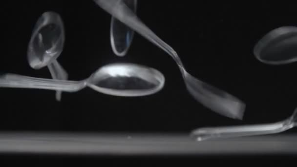 Cuillères transparentes tombe sur fond noir ralenti vidéo . — Video