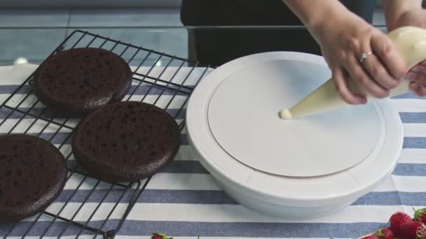 Profi-Koch kocht Kuchen. Junge attraktive Hausfrau legt weiße Sahne auf Teller und legt Teil auf Kuchen drauf — Stockvideo