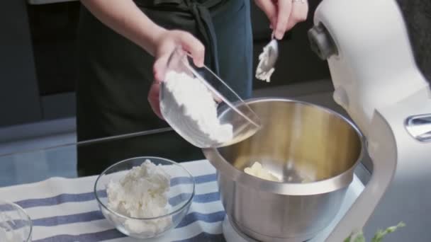 Professionele chef-kok kookt taart. jong aantrekkelijk huisvrouw zet ingrediënten naar mixer kom naar maakt een witte crème — Stockvideo