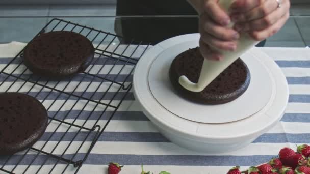 Professional chef is cooking cake. Young attractive housewife puts white cream on chocolate cake — Stock Video