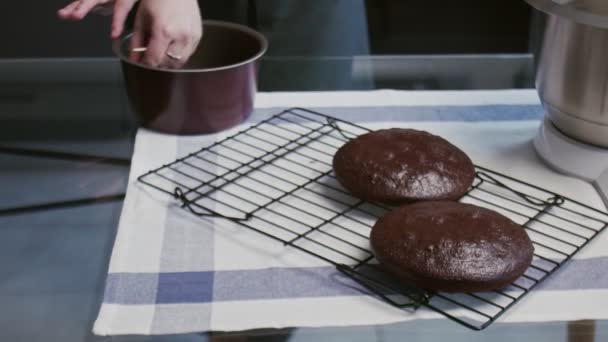 Професійний шеф-кухар готує торт. Молода приваблива домогосподарка перевіряє варений торт з дерев'яною паличкою і кладе його на металеву сітку — стокове відео