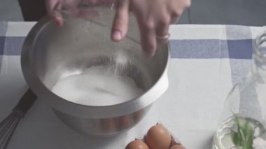 Profesyonel şef kek pişiriyor. Genç çekici ev hanımı metal kaseye şeker ve yağ koyuyor.