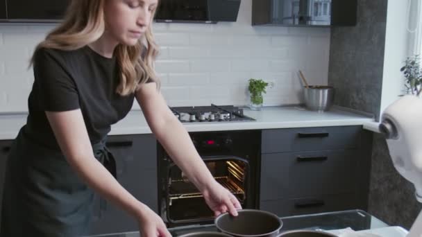 Profi-Koch kocht Kuchen. Junge attraktive Hausfrau stellt drei Backformen mit Teig in den Ofen — Stockvideo