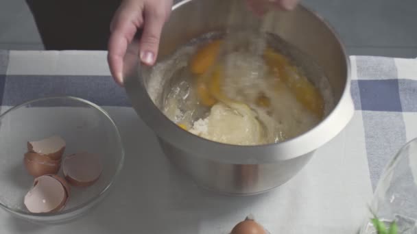 Επαγγελματίας σεφ μαγειρεύει κέικ. Νεαρή ελκυστική νοικοκυρά χρησιμοποιεί το σύρμα για να αναμίξει ζάχαρη, αυγά και λάδι σε μεταλλικό μπολ — Αρχείο Βίντεο