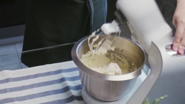 Lo chef professionista sta cucinando la torta. Giovane casalinga attraente accendere mixer professionale con ingredienti per fare una crema bianca — Video Stock