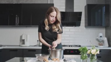 Profesyonel şef kek pişiriyor. Genç ve çekici ev hanımı çikolatalı pasta için hamur karıştırıyor.