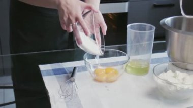 Profesyonel şef kek pişiriyor. Genç ve çekici ev hanımı şeker ve yumurtayı kaseye karıştırmak için çırpıcı kullanır.