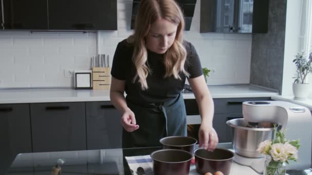 Profesjonalny kucharz gotuje ciasto. Młoda atrakcyjna gospodyni domowa umieszcza papier do pieczenia w trzech patelni — Wideo stockowe
