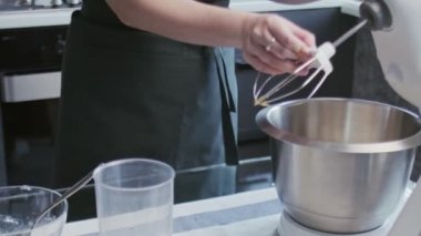 Profesyonel şef kek pişiriyor. Genç ve çekici ev hanımı profesyonel miksere metal çırpıcı yerleştiriyor.