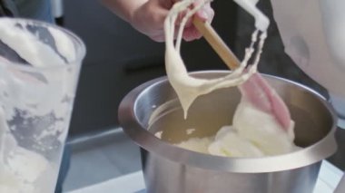 Profesyonel şef kek pişiriyor. Genç ve çekici ev hanımı profesyonel miksere beyaz krema koyar.