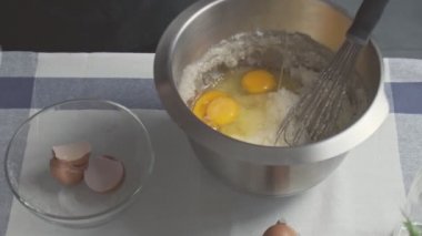 Profesyonel şef kek pişiriyor. Genç çekici ev hanımı karışık yağ ve şekere yumurta ekler.