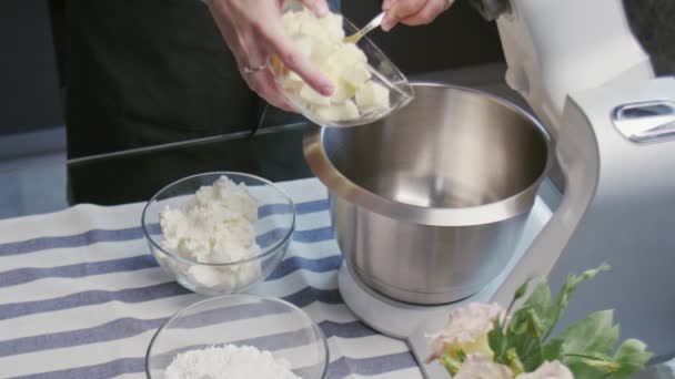 Chef profissional está cozinhando bolo. Jovem chef atraente coloca manteiga para misturador profissional — Vídeo de Stock