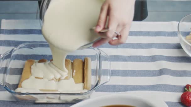 Profi-Koch kocht Tiramisu-Kuchen. Junge attraktive Hausfrau gießt weiße Sahne auf Tiramisu — Stockvideo