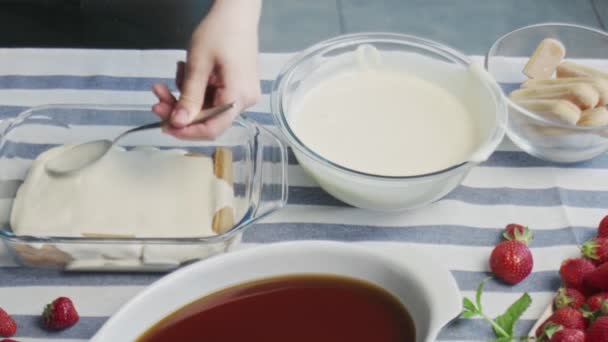 Profi-Koch kocht Tiramisu-Kuchen. Junge attraktive Hausfrau gießt weiße Sahne auf Tiramisu — Stockvideo