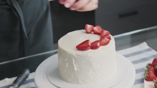 A profi séf tortát főz. Közelkép a nő helyek eper tetején egy gyönyörű fehér torta egy modern konyhában — Stock videók