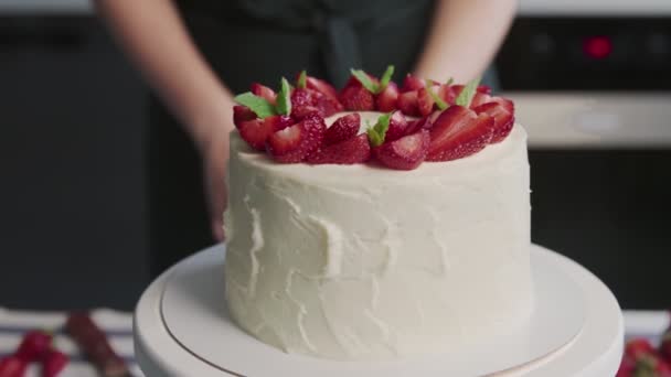 Профессиональный повар готовит торт. Закрыть красивый белый торт с клубникой сверху на современной кухне — стоковое видео