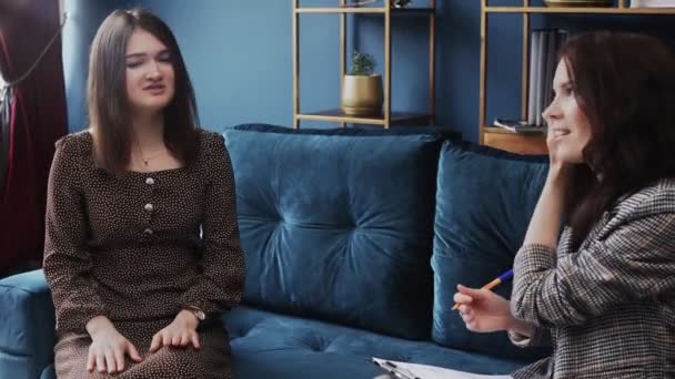Attraktive junge Frau sitzt auf bequemer Couch und trifft Psychologin. — Stockvideo