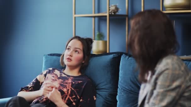 Tonåring med smärta. En tonåring med smärtor och problem sitter i soffan och pratar med psykolog. — Stockvideo