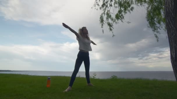 Молодая женщина практикует медитацию и йогу на природе на высокой скале у моря . — стоковое видео