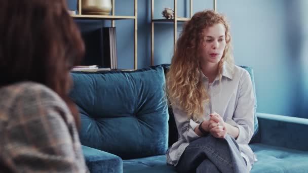 O tânără supărată stând în poziție închisă pe canapea și vorbind cu psihologul la sesiunea de terapie — Videoclip de stoc