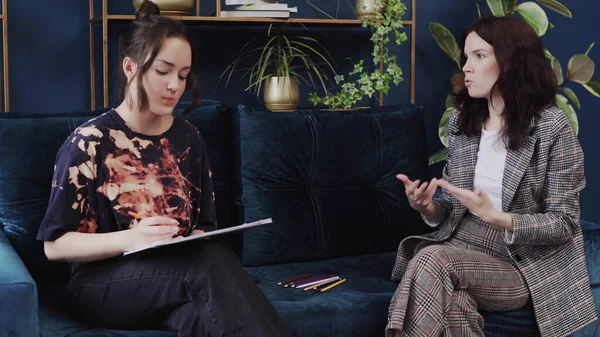 Genç bir kız çocuk psikoloğuyla terapi görüyor. Çizim testini yapıyor.