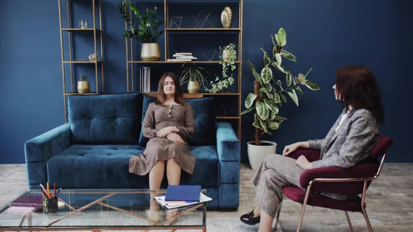 Young woman with closed eyes lying on sofa and listening psychologist at therapy session — Stock Photo, Image