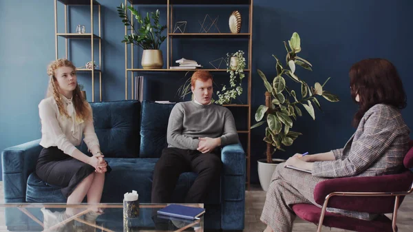 Kadın psikolog endişeli genç çifte yardım ediyor. Aile terapisi. Genç adam ailesindeki sorunlardan bahsediyor..