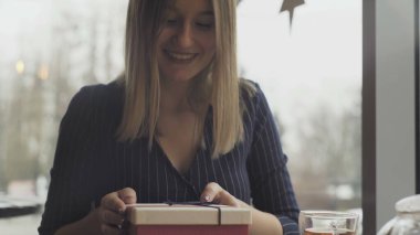 Erkek arkadaşı restorandaki gülümseyen kız arkadaşına hediye veriyor.