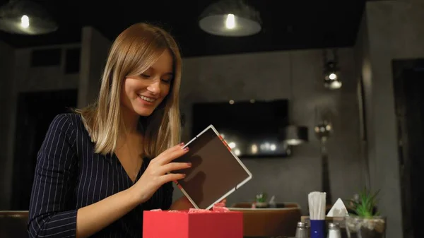 Boyfriend giving gift to his smiling girlfriend at reastaurant Stock Image