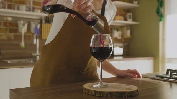 Vrouw schenkt een glas rode wijn in luxe huis — Stockfoto