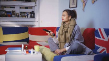 Hasta genç kadın televizyon seyrediyor ve hap alıyor.