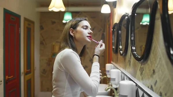 Woman applying lipstick in hostel toilet — Stock Photo, Image