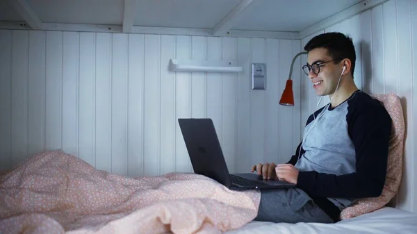 침대에 누워 인터넷 카메라로 얘기하고 웃고 있는 남자 — 스톡 사진
