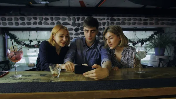 Friends using smartphone at bar counter in pub — Stock Photo, Image