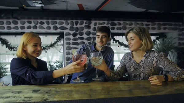 Two women and one man are sitting at the bar counter and drinking cocktails — Stock Photo, Image