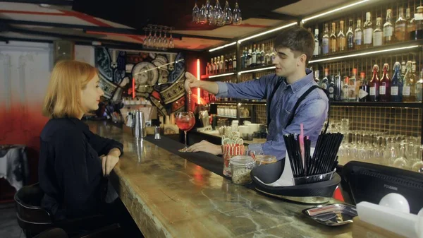 Привлекательной женщине подают коктейли в баре. Бармен делает коктейль гостю . — стоковое фото