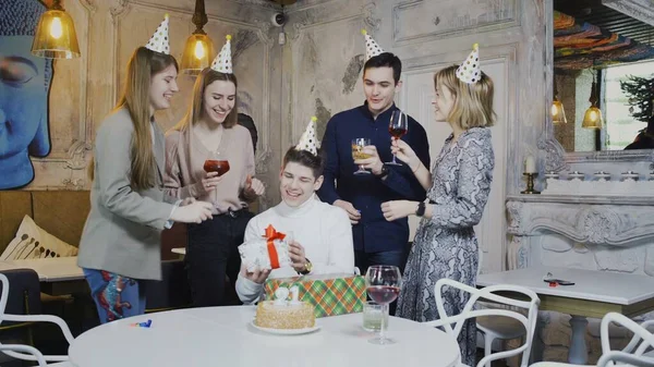 Smiling friends giving presents to birthday man, having party time at the weekend in cafe — Stock Photo, Image