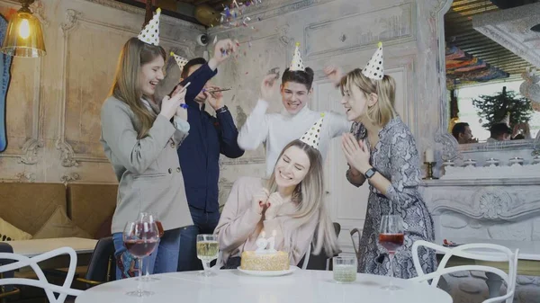 Opgewonden mooie vrouw blazen verjaardag kaarsen terwijl dierbaarste vrienden gooien verrassing partij — Stockfoto