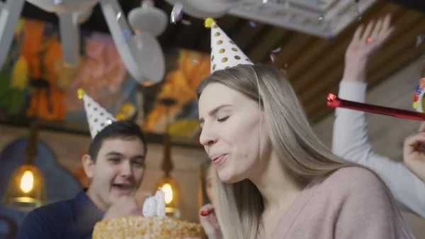 Jovem loira está fazendo desejo e soprando velas queimando no bolo de aniversário — Fotografia de Stock