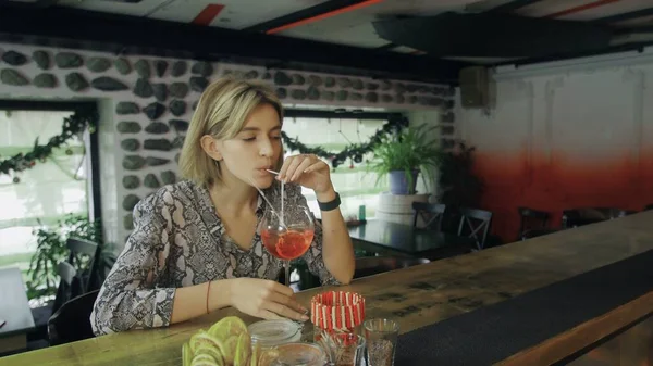 Single seductive blonde female sitting at bar counter while bartender giving prepared cocktail. — Stock Photo, Image