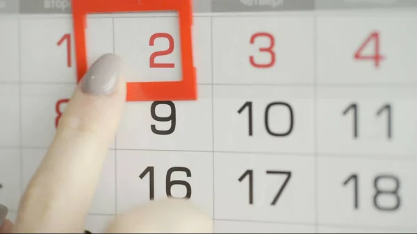 Womans hand in office changes date at wall calendar. 2