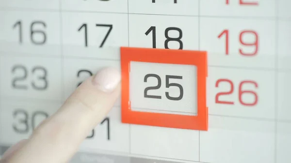 Kvinna hand i kontor ändrar datum på vägg kalender. 25 — Stockfoto