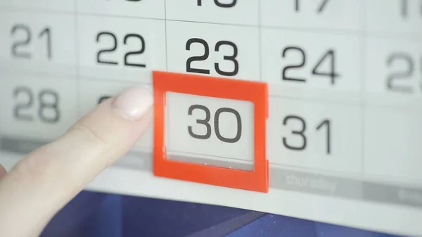 Womans hand in office changes date at wall calendar. 30